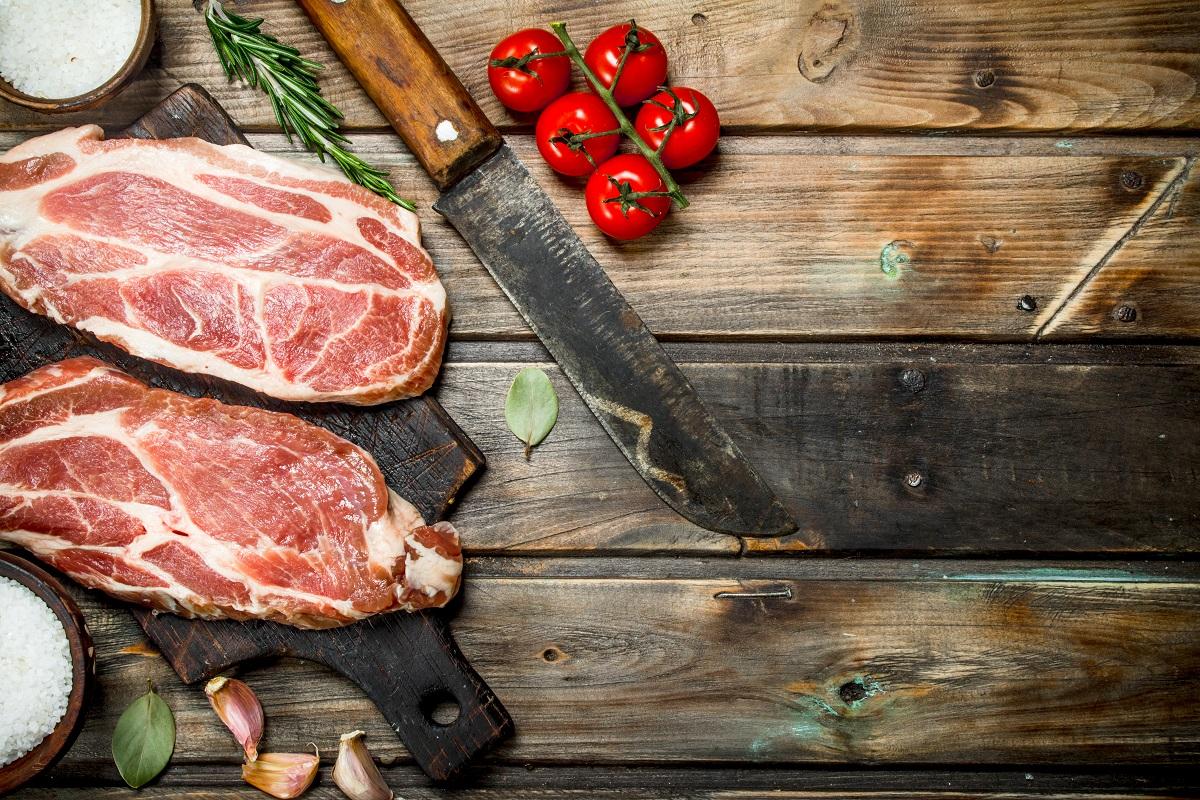 Raw pork steaks with tomatoes and spices.